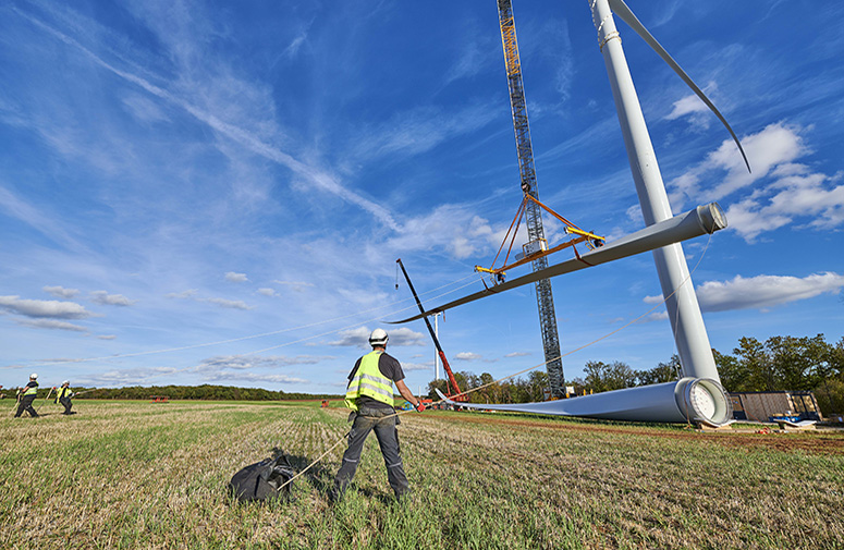 ouvrier levant une pale d'éoliennes